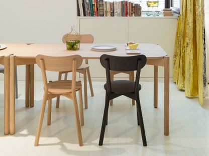 Chaises Castor en chêne et noire autour d'une table, devant une bibliothèque | Antifer
