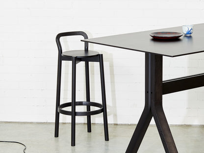 Tabouret Castor noir et table haute noire devant un mur de briques, vue d'ensemble | Antifer