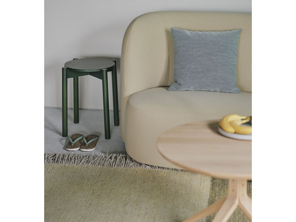 Tabouret Castor Plus vert derrière un canapé beige, avec table basse en chêne | Antifer