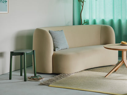 Tabouret Castor Plus vert en bout de canapé beige, devant un rideau vert d'eau | Antifer