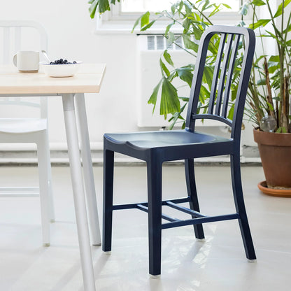 Close-up of a large table with an Emeco 111 Navy chair in recycled rPET plastic, navy blue. Coffee on the table | Antifer