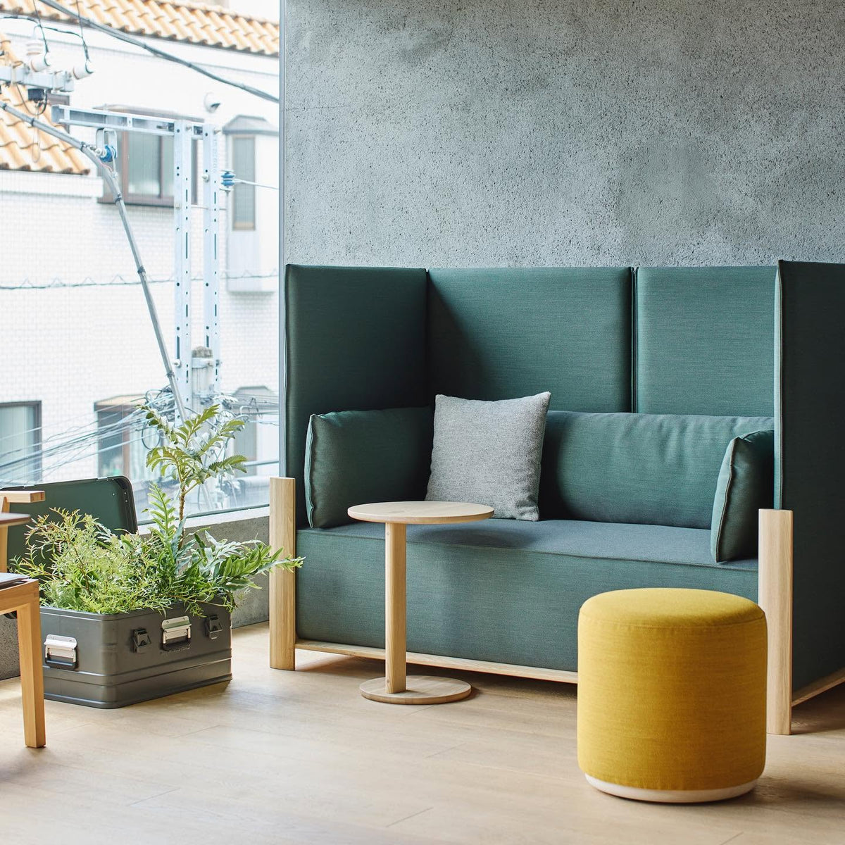 Canapé Fence vert d'eau sur une terrasse couverte, avec guéridon en chêne et pouf jaune | Antifer