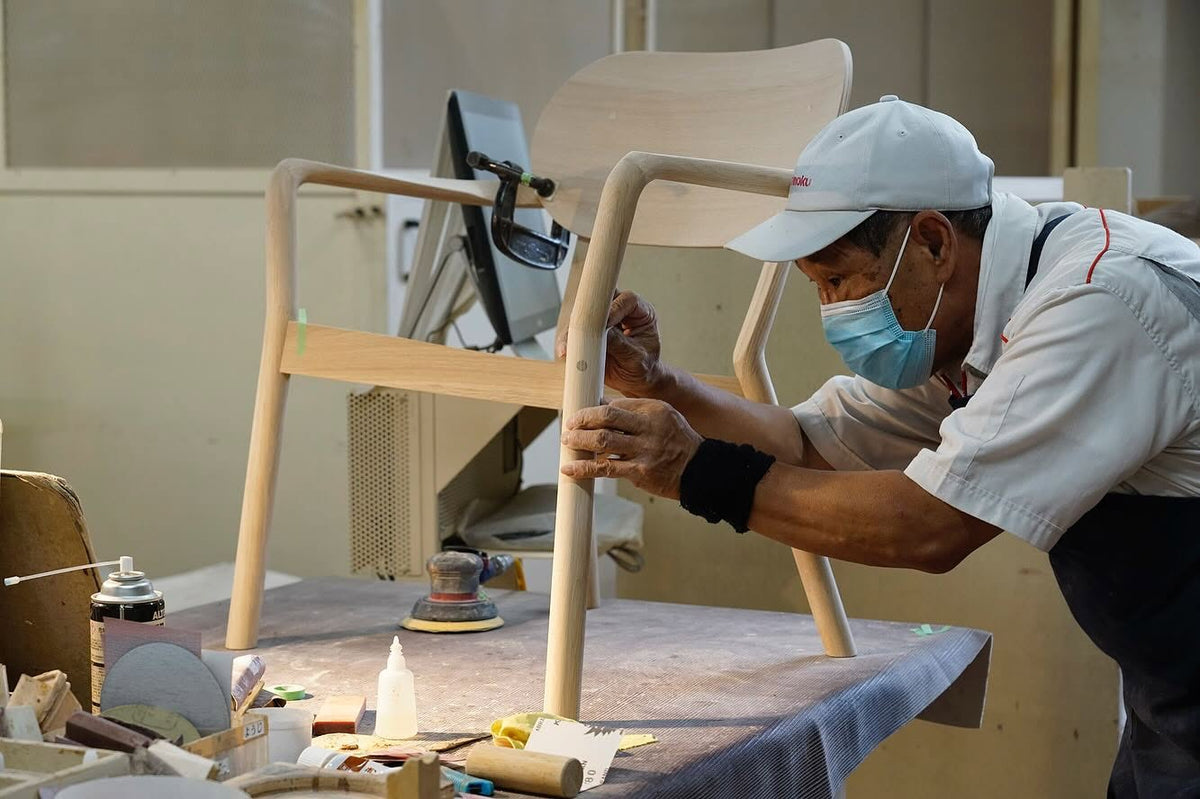 Fauteuil Castor Armchair Plus en cours de ponçage à l'établi, dans l'atelier Karimoku | Antifer