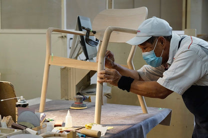 Fauteuil Castor Armchair Plus en cours de ponçage à l'établi, dans l'atelier Karimoku | Antifer