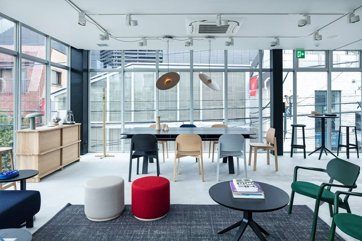 Portemanteau Signs dans un showroom vitré, avec table Castor, poufs colorés et chaises Polar | Antifer