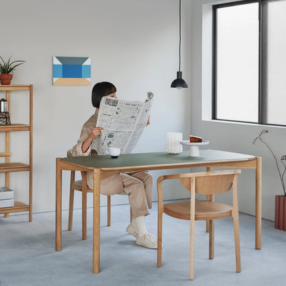 Table Castor 180 à plateau linoléum vert dans un intérieur clair, une femme y lit le journal | Antifer