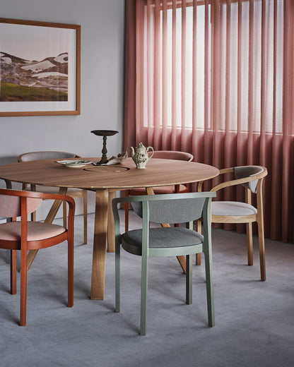 Table ronde en chêne dans une salle à manger à rideau rose, entourée de chaises Chesa — Karimoku New Standard | Antifer
