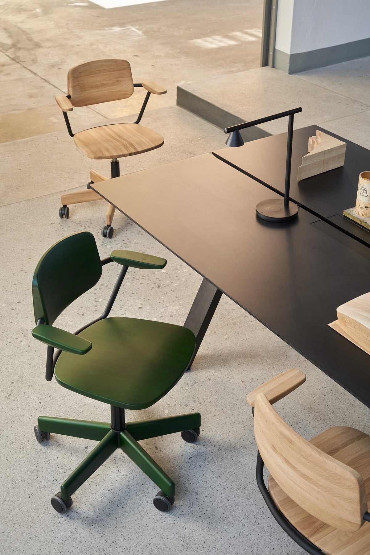 Bureau Spectrum noir vu de dessus, avec siège de bureau vert à roulettes et lampe articulée — Karimoku New Standard | Antifer