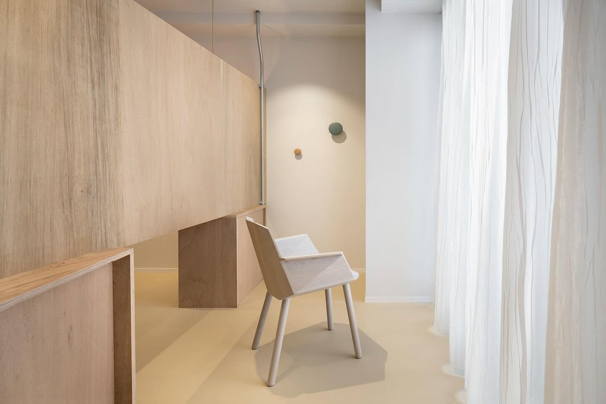 Fauteuil Colour Wood seul dans un couloir clair, près d'un voilage et d'une applique | Antifer