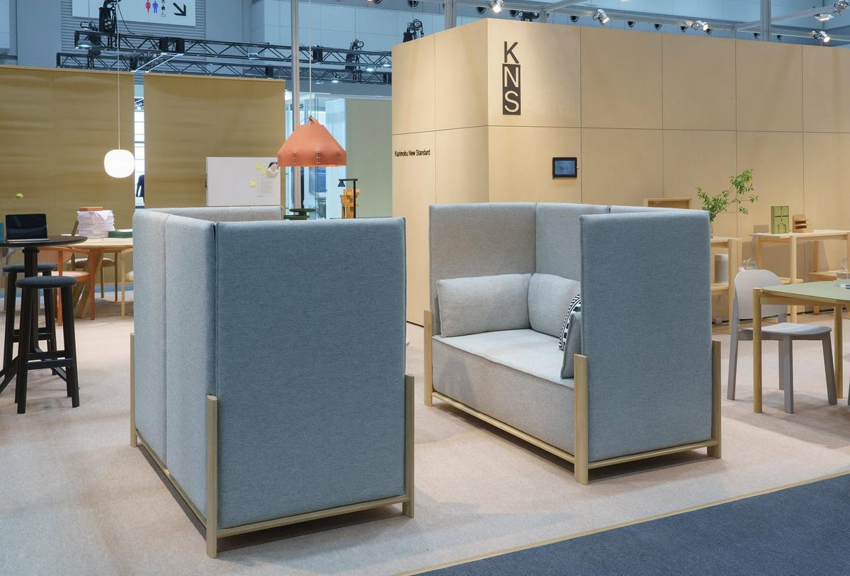 Stand Karimoku New Standard sur un salon, canapés à dossier haut gris et socle en chêne — Karimoku New Standard | Antifer