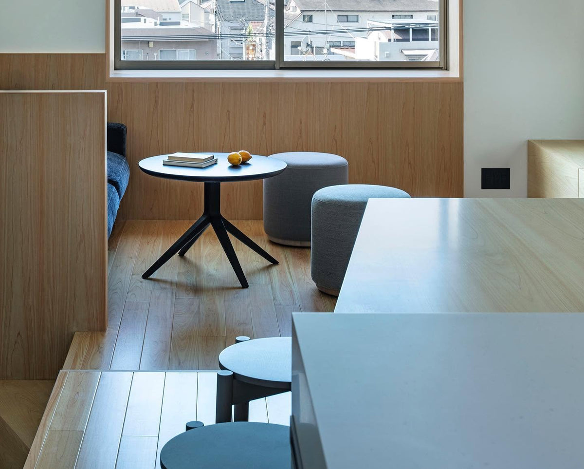 Table bistrot Scout à plateau noir dans un espace lambrissé, avec poufs Elephant bleus — Karimoku New Standard | Antifer