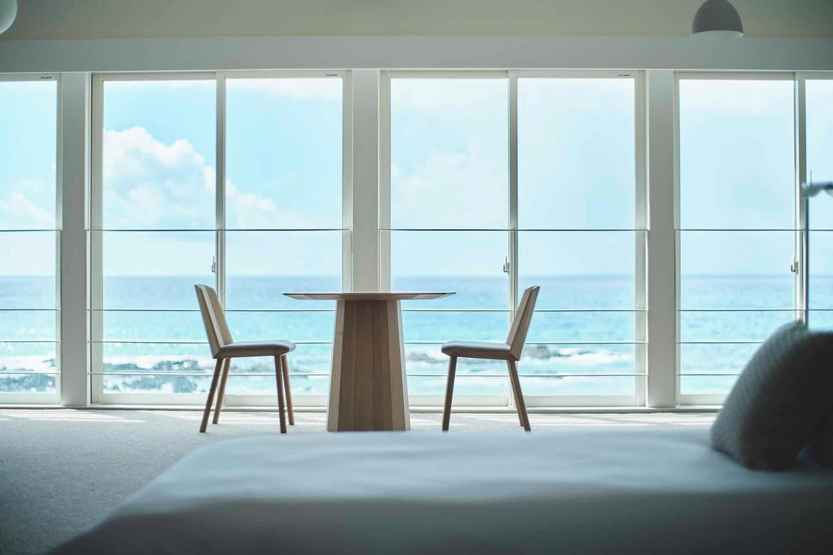 Table bistrot Scout et deux chaises Castor devant la baie vitrée d'une chambre face à la mer | Antifer