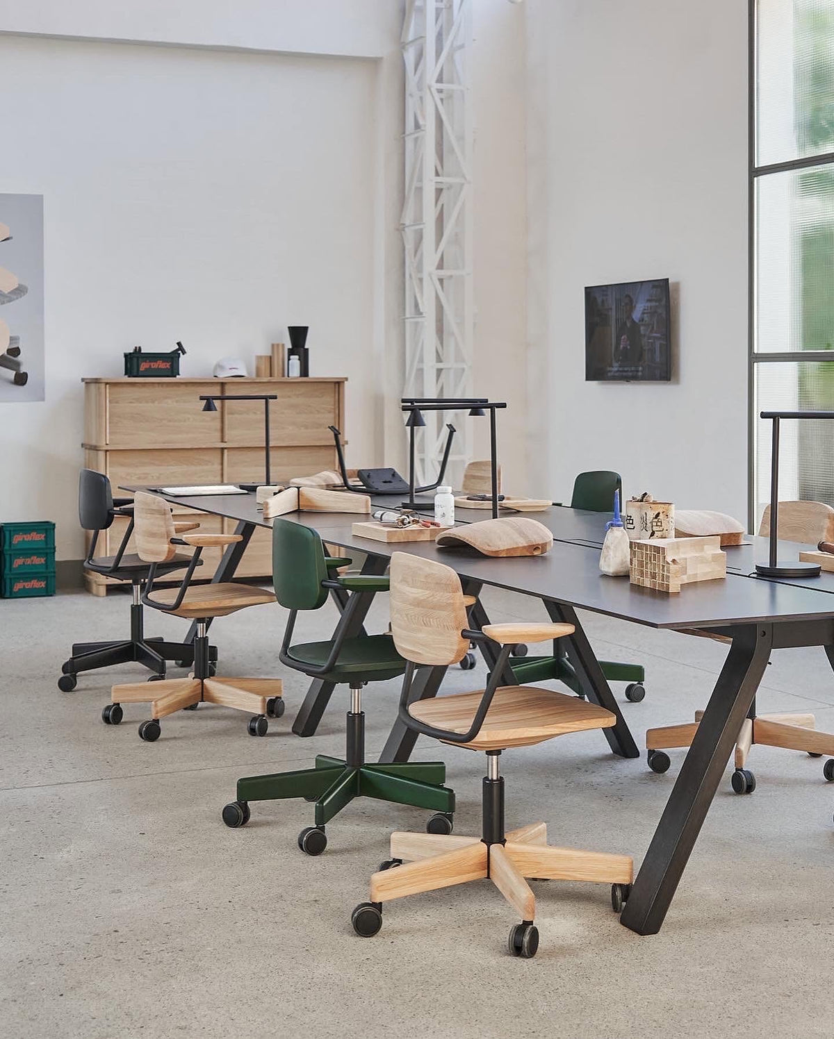 Bureau Spectrum noir en table partagée dans un atelier, entouré de sièges à roulettes — Karimoku New Standard | Antifer