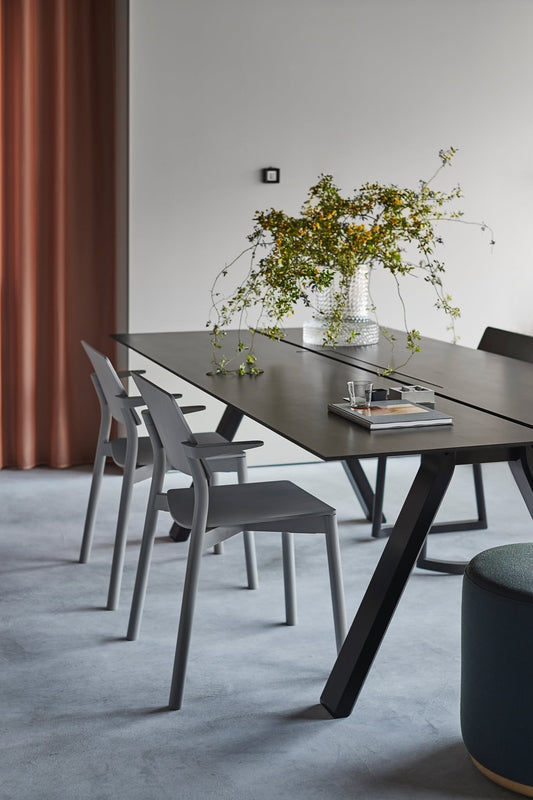 Bureau Spectrum noir devant un rideau terracotta, avec chaises grises et pouf Elephant — Karimoku New Standard | Antifer