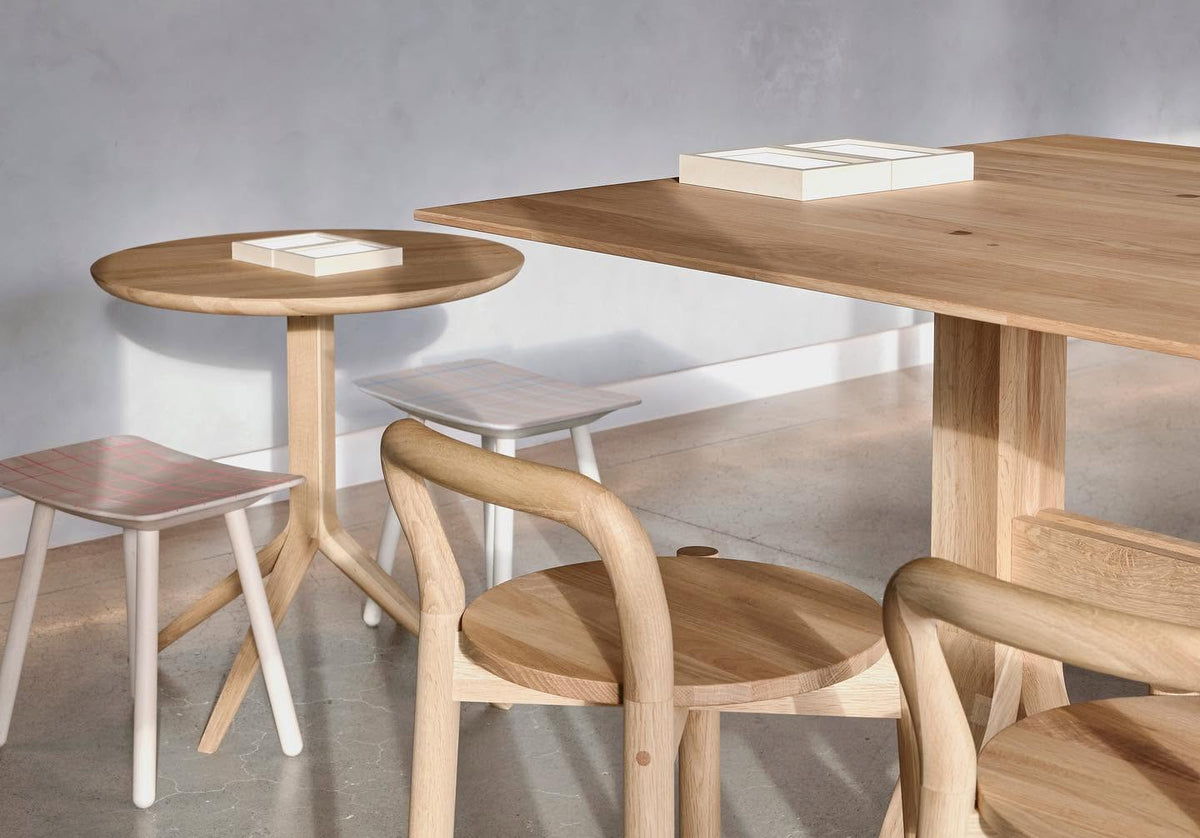 Table bistrot Scout au premier plan d'un café, avec tabourets et fauteuils Castor en chêne | Antifer