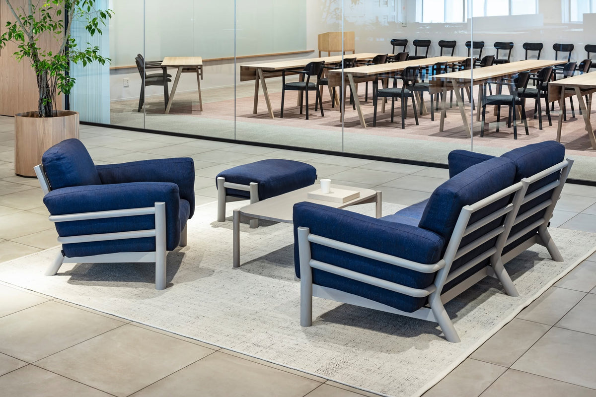 Lounge d'entreprise à fauteuils bleus, enfilade de tables et de chaises au fond — Karimoku New Standard | Antifer