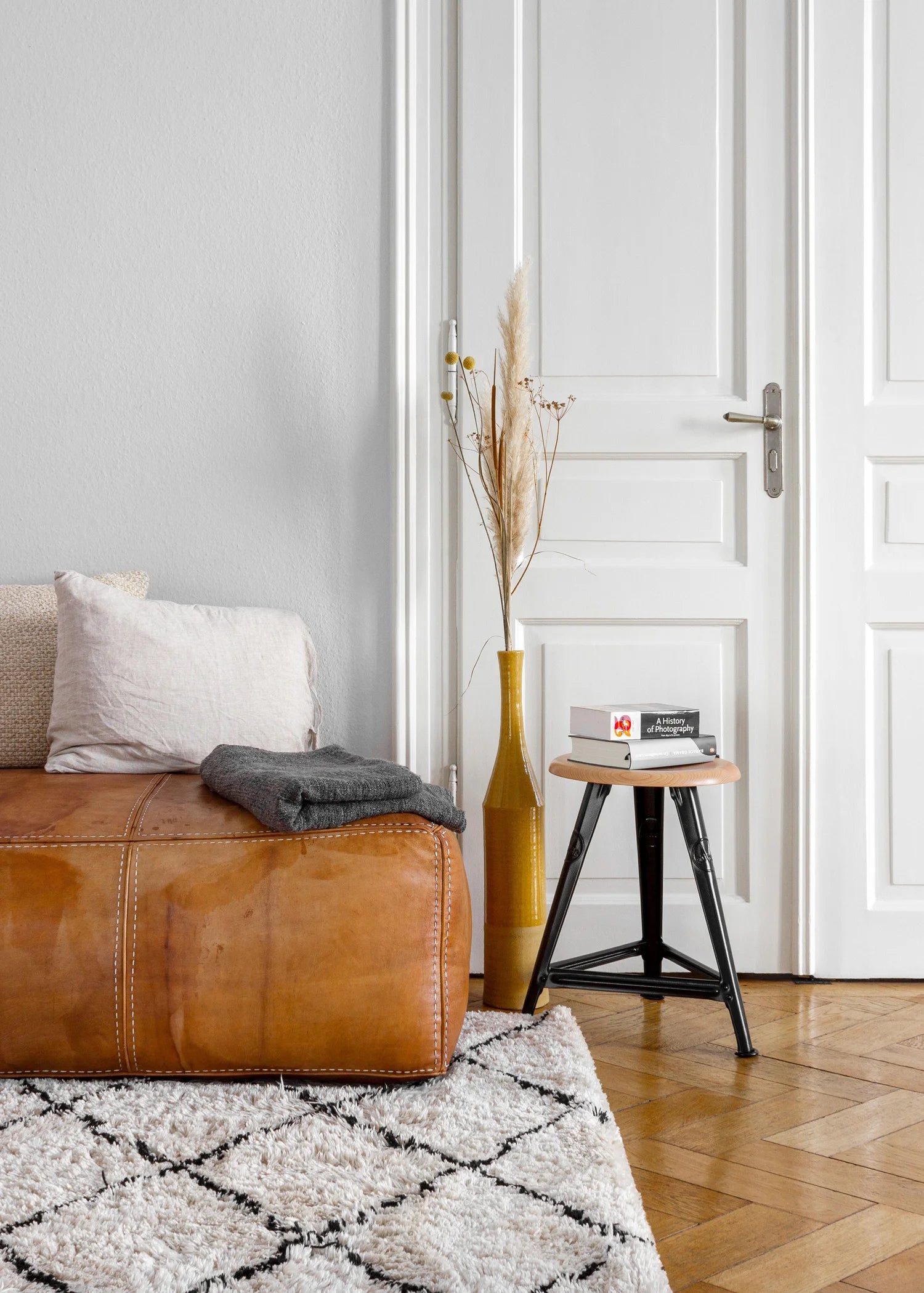 Detalle taburete Rowac Schemel en un interior loft — alianza madera y acero remachado, diseño industrial atemporal