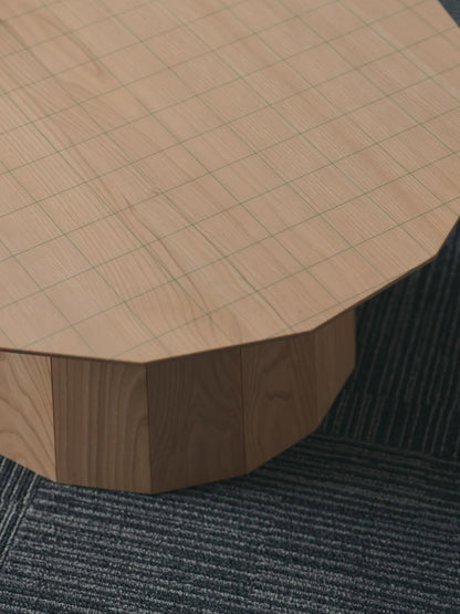 Table Colour Wood ø120 — détail du plateau quadrillé et du fût conique, posée sur une moquette sombre | Antifer